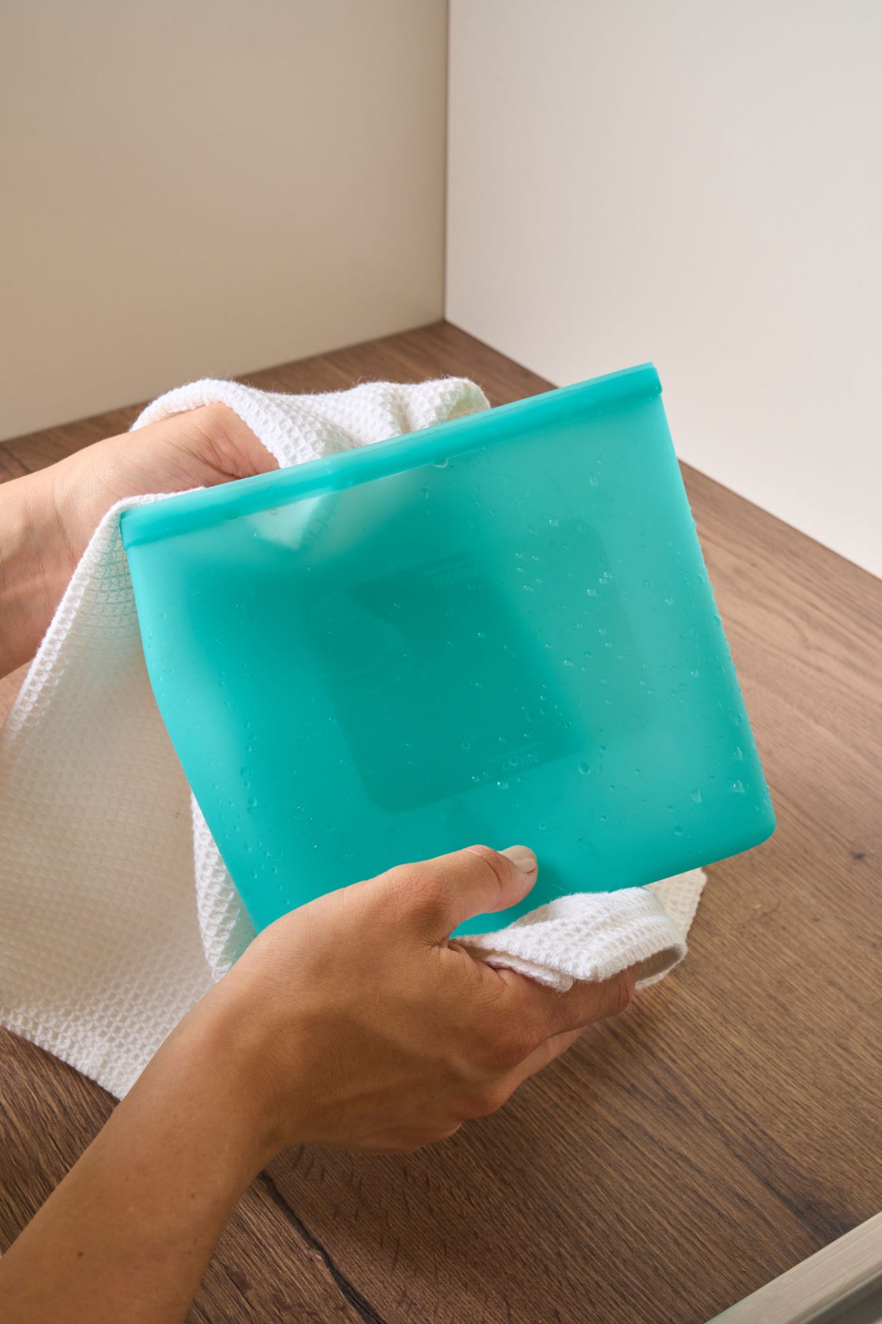 Eine Person trocknet einen wiederverwendbaren Toppits Silikonbeutel mit einem weißen Tuch ab