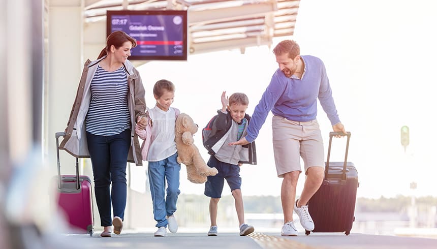 Fröhliche Familie mit Koffern am Bahnhof