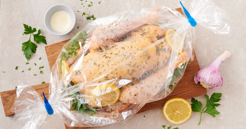 Ungegartes Hähnchen im Toppits Bratschlauch, dabei Zitrone, Petersilie und Knoblauch