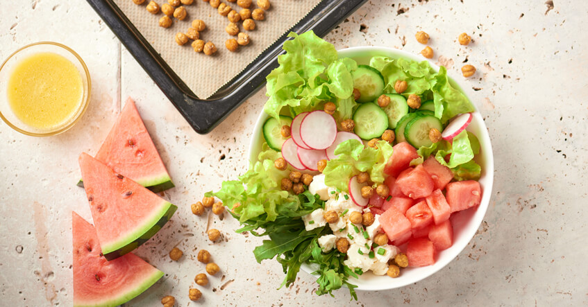 Geröstete Kichererbsen auf Backblech und Sommersalat in der Bowl