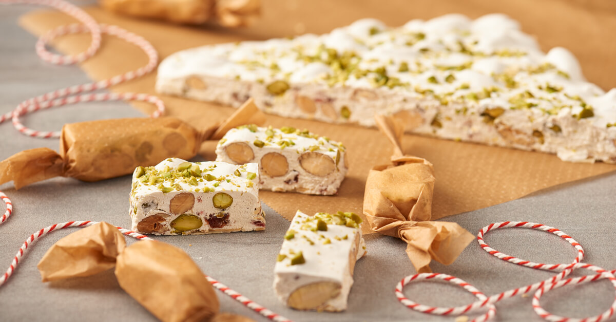 Weißer Nougat oder Turron mit Mandeln und Pistazien auf Backpapier