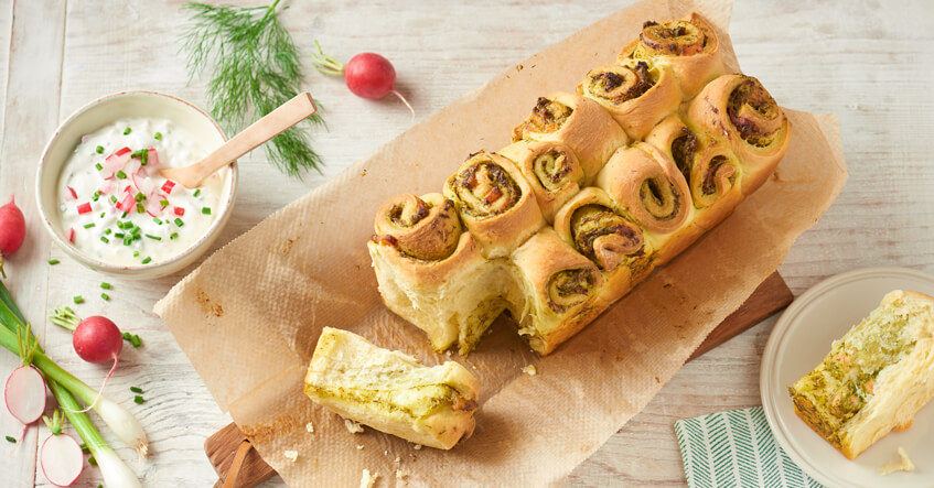 Zupfbrot auf Backpapier mit Kräuter-Dip in der Schüssel